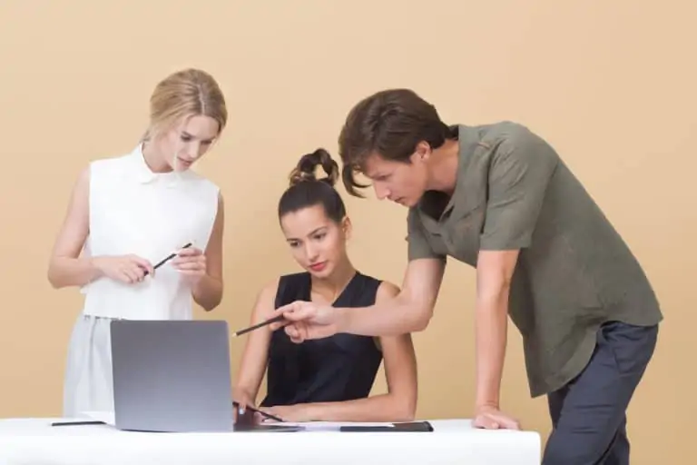 Drei Menschen stehen vor einem Laptop und schauen auf den Bildschirm